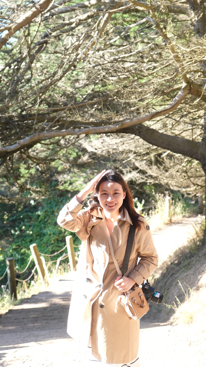 Xi Guan standing outdoors on a tree-lined path